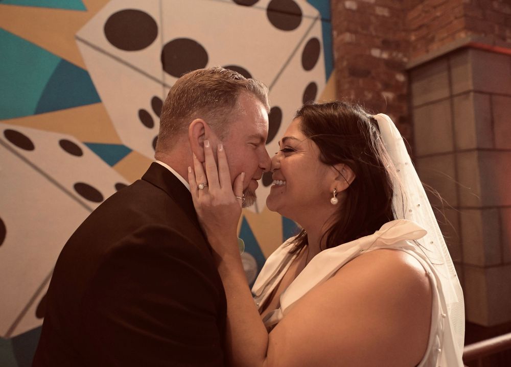 Bride and groom share an intimate moment, nearly kissing, with a colorful dice mural backdrop at a Las Vegas wedding.