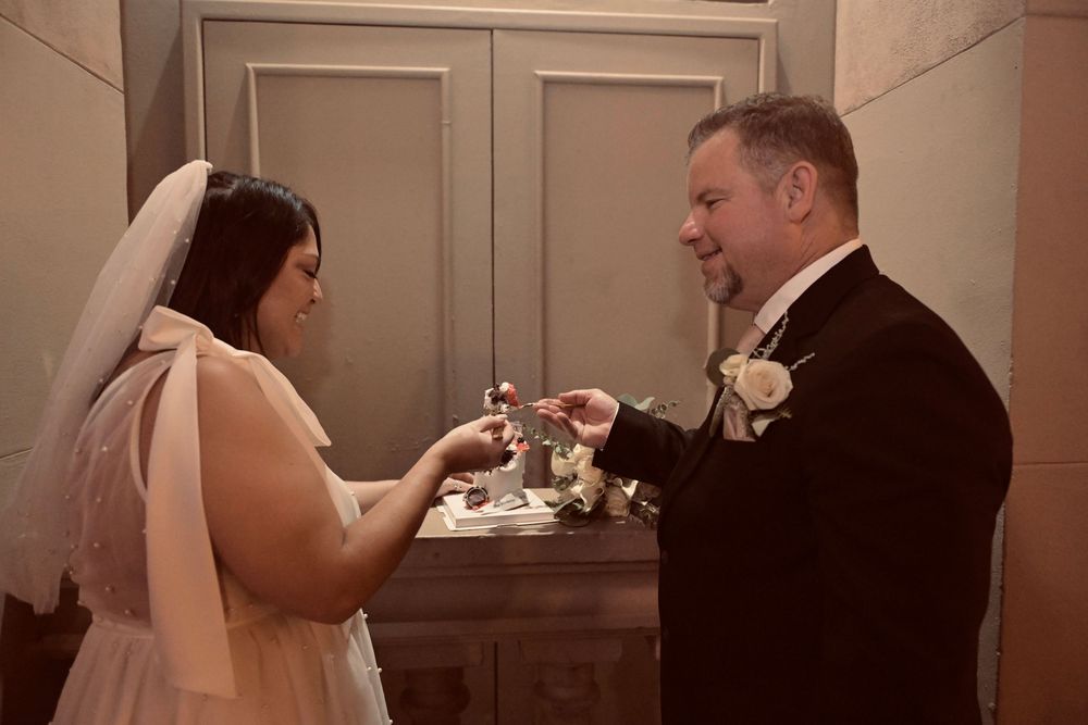 Bride and groom exchanging rings during an intimate indoor wedding ceremony, bride wearing white gown and veil.