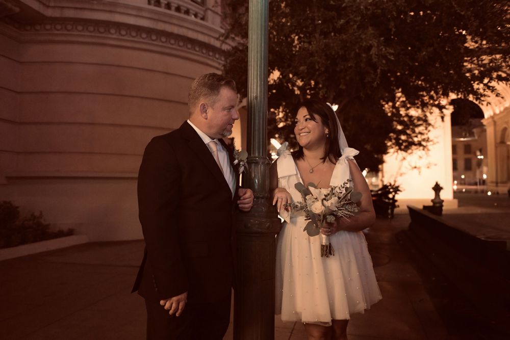 Bride and groom lean against a lamppost at night, gazing at each other during their Las Vegas wedding.