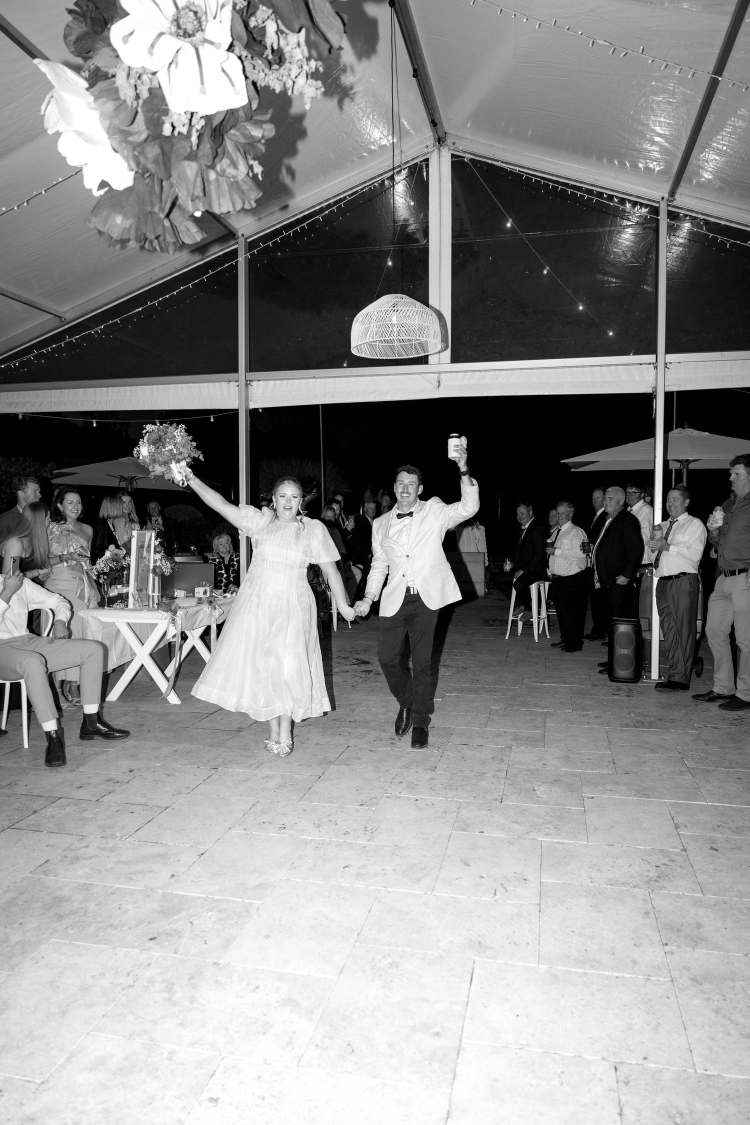 Bride and groom celebrate their first dance entrance at an elegant tented wedding reception in black and white.