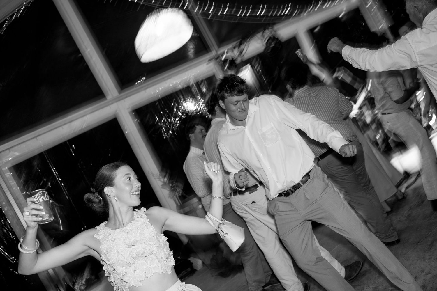 Bride and groom dance energetically at their wedding reception in a black and white photo.