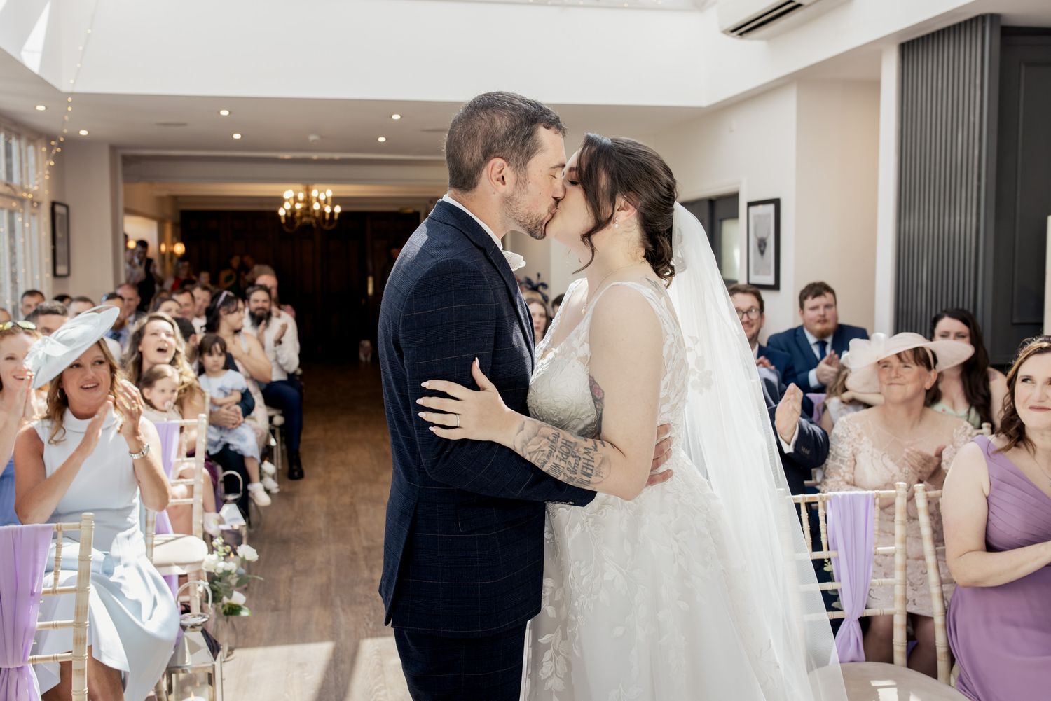 Newlyweds sharing their first kiss during their wedding ceremony at Broadoaks Country House