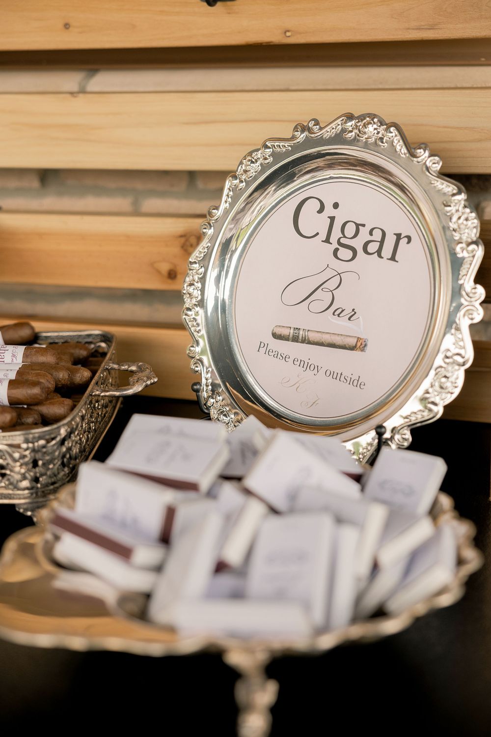 Elegant silver framed Cigar Bar sign displayed at a wedding reception with chocolates and cigars on decorative trays.
