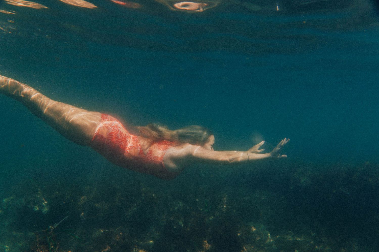 Photo of a woman in Elation the Label surf suit diving into the vast blue ocean in Newcastle, NSW