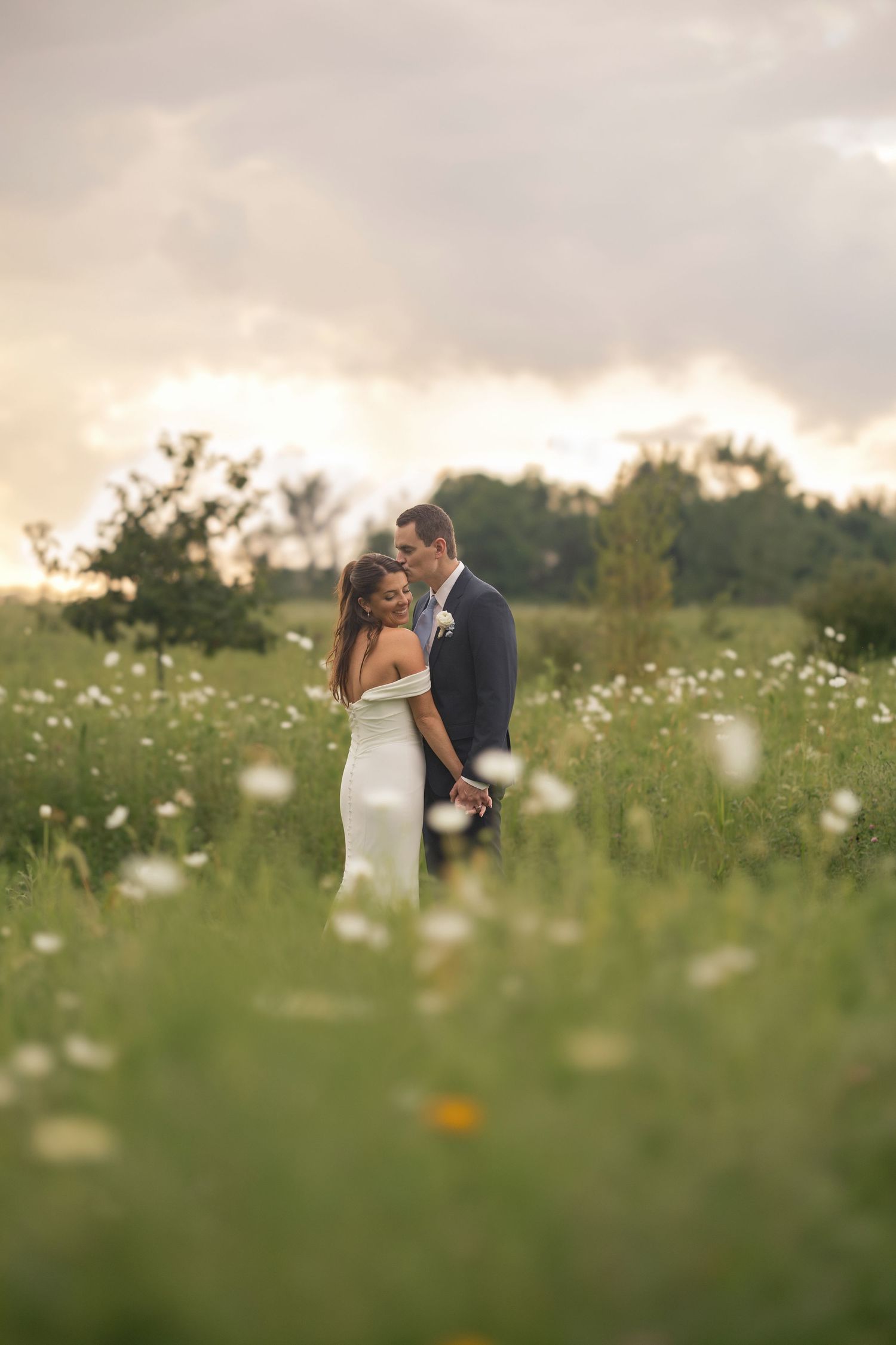 Bride and groom at sunset in a field of white wildflowers at their Magnolia Hill Farm wedding in Centerburg, Ohio.