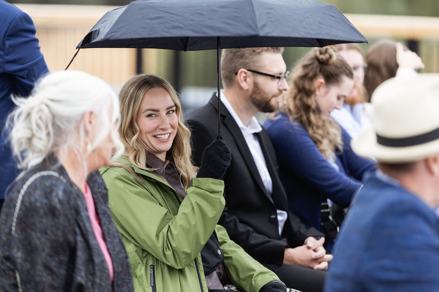 Wedding guests laughing under umbrellas during a rainy Canmore wedding ceremony