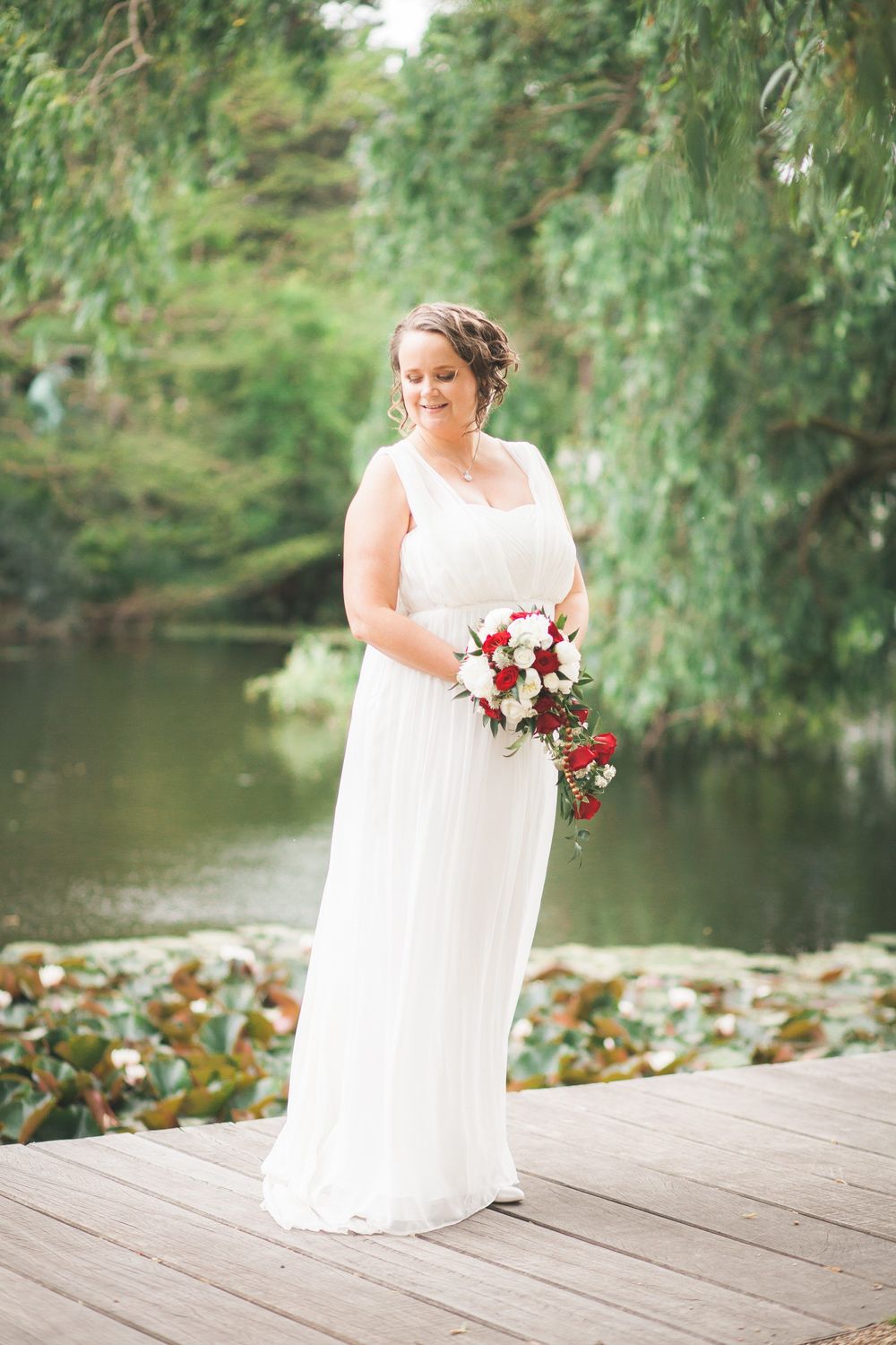 Brud med buket ved vandet – bryllupsfoto af Martin & Louise