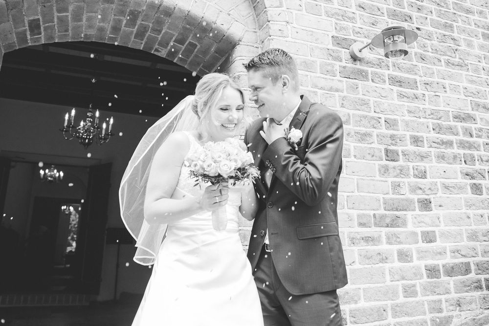 Brudepar ved murstensbue i sort/hvid – bryllupsfoto af Martin & Louise