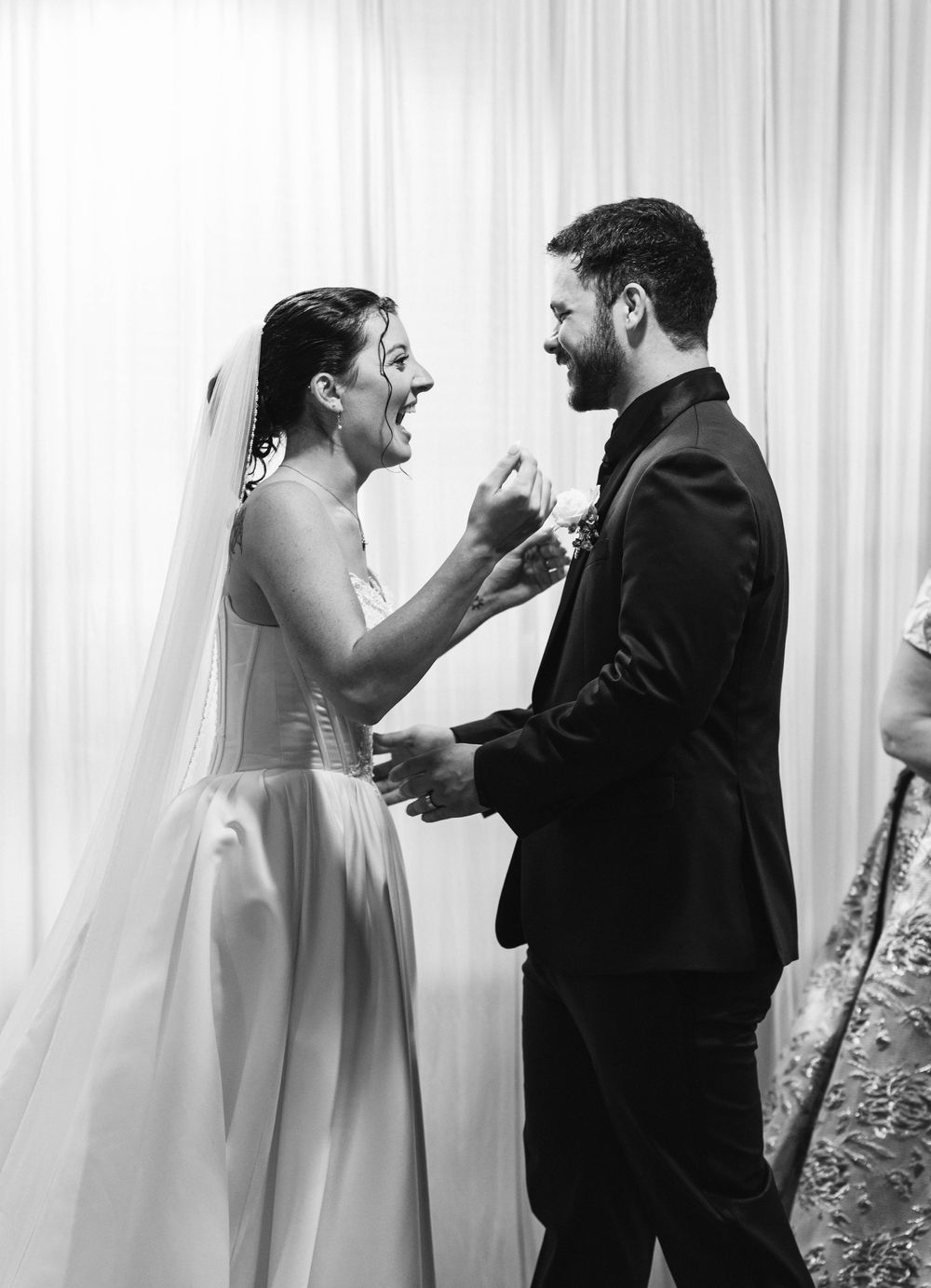 Bride and groom laughing joyfully during wedding reception in black and white.
