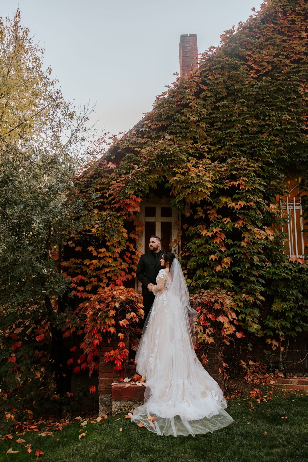 bride and groom standing on steps of an old church covered in colored foliage on their autumn nothern california elopement day