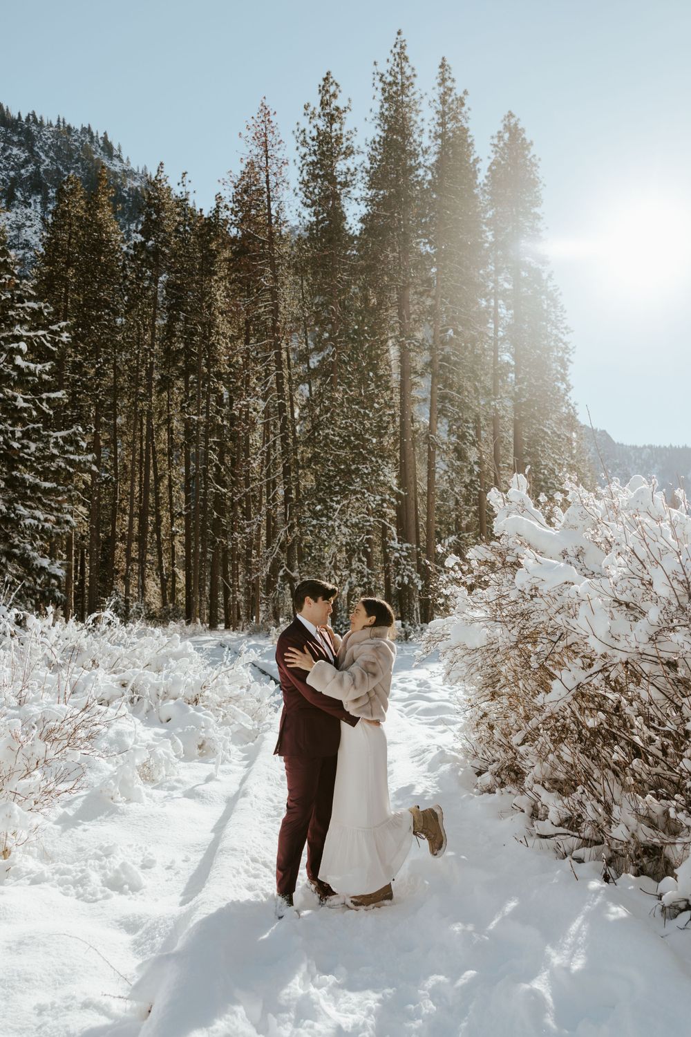 couple standing on the snow with trees behind them during their winter yosemite elopement day