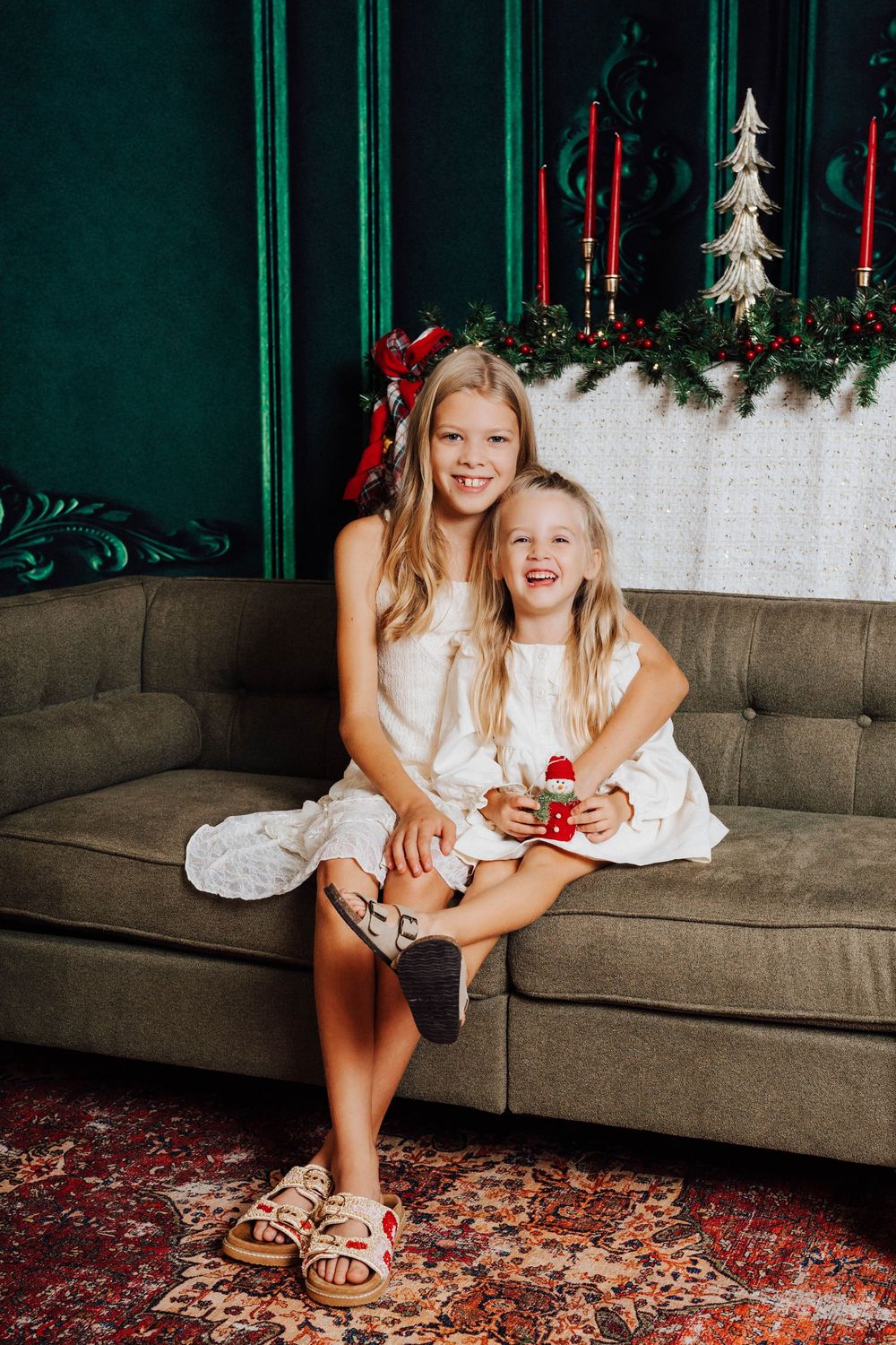Two sisters smiling with in a festive Christmas studio portrait in Middletown, PA at Nicolle Aponte Photography's studio.