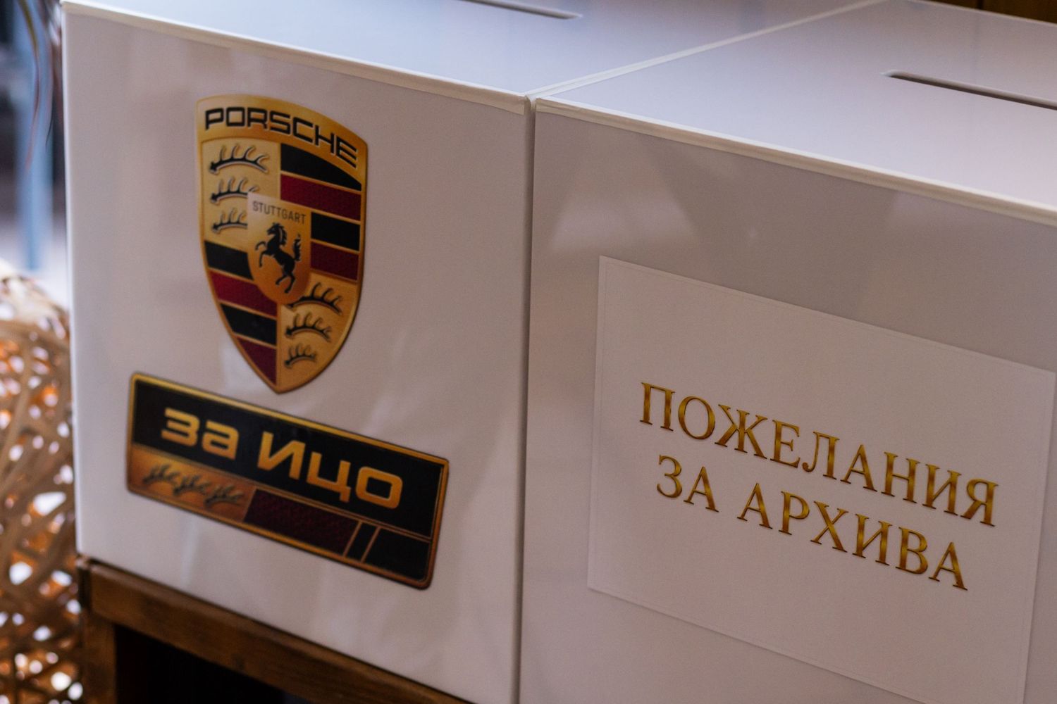 Porsche branded white boxes with Cyrillic text at an event, featuring the iconic Porsche crest logo.