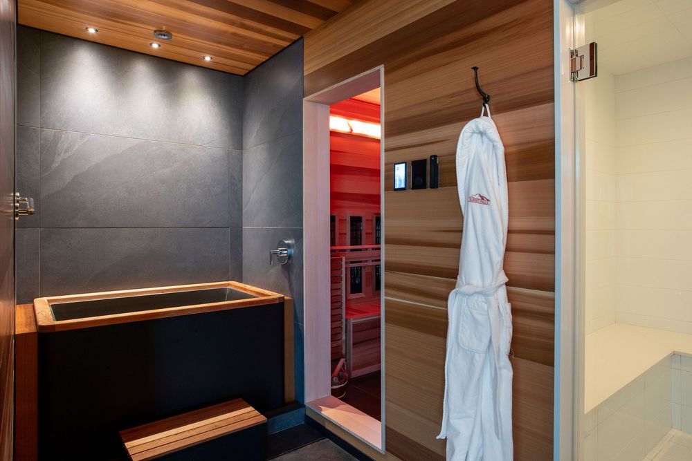 Luxury spa bathroom with Japanese soaking tub, cedar sauna with red light therapy, and slate tile walls.