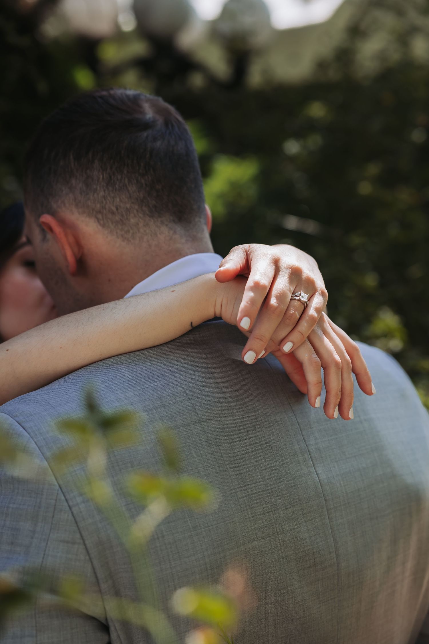 Bride and groom holding hands walking on green grass near a pond at sunset during outdoor wedding.