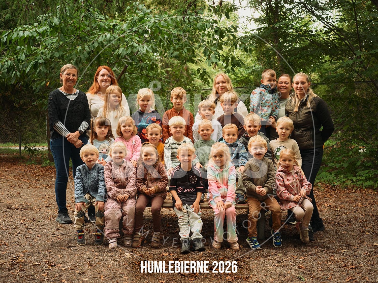 Group photo of children and teachers from Humlebierne 2026 class posing outdoors in a forest setting.