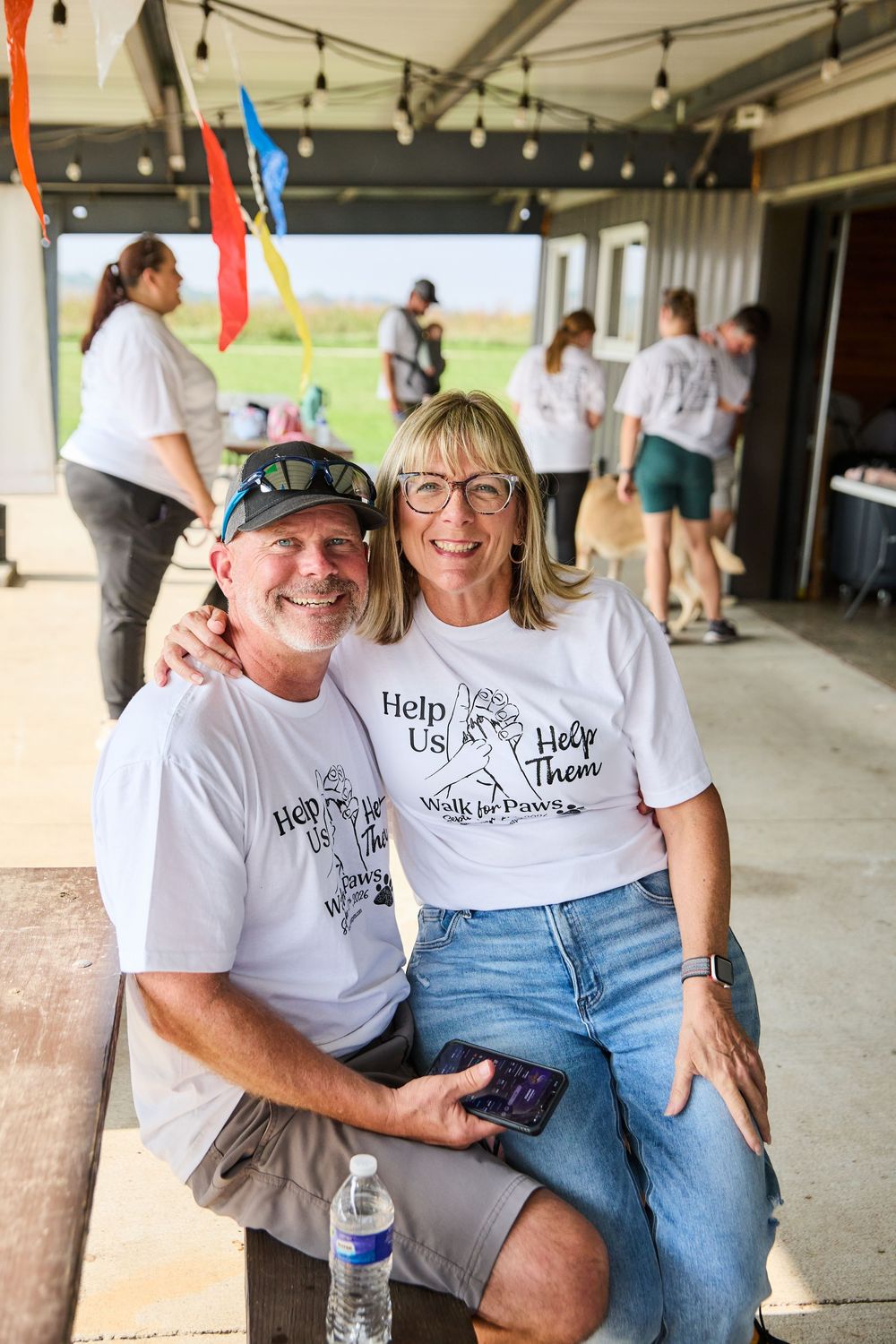 Couple smiling in matching Walk for Paws charity event white t-shirts at an outdoor fundraiser venue.
