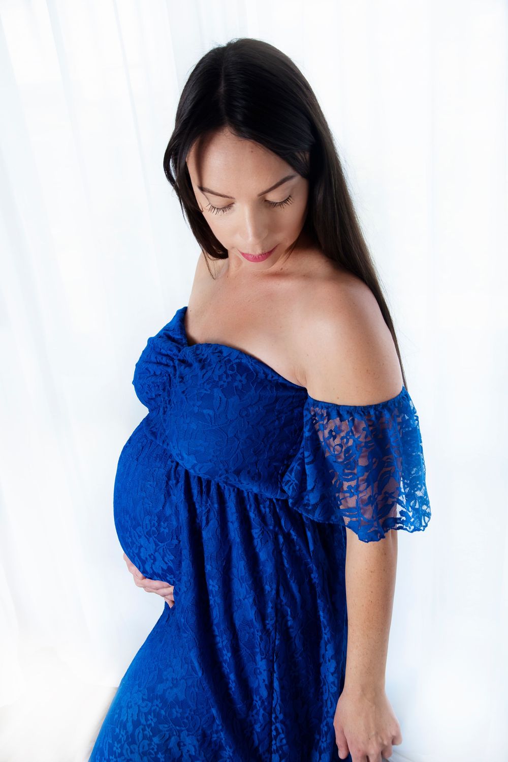 a pregnant mother for her studio maternity session wearing a lace blue dress