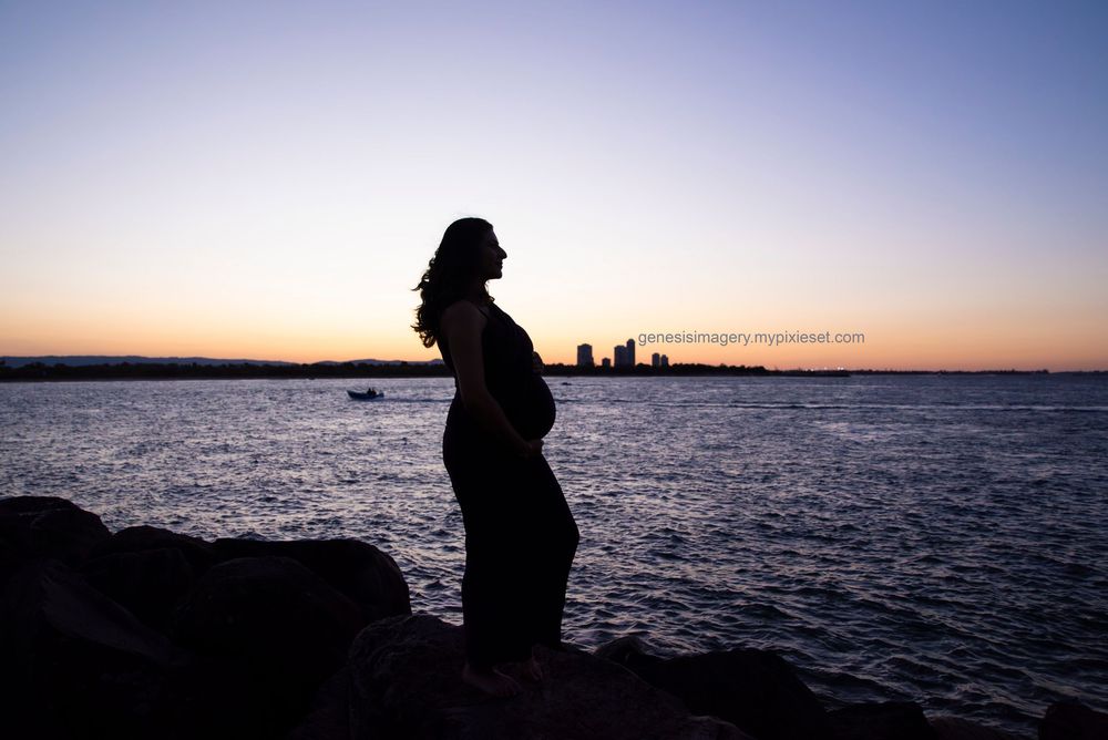 silhouette at sunset of a pregnant mother with the the gold coast skyline in the background