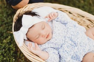 Newborn baby girl sleeping peacefully in a wicker basket outdoors at Melton Hill Park in Knoxville, TN with Nina Thomas Photography