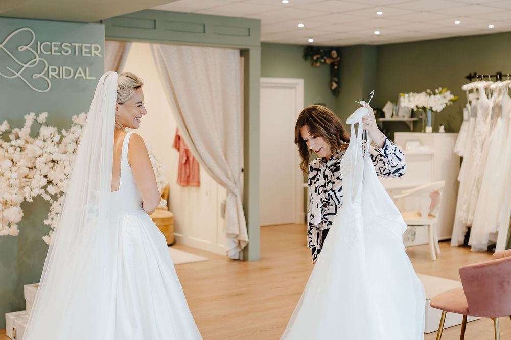 Bridal consultant showing a wedding dress to a bride trying on gowns at Leicester Bridal boutique.