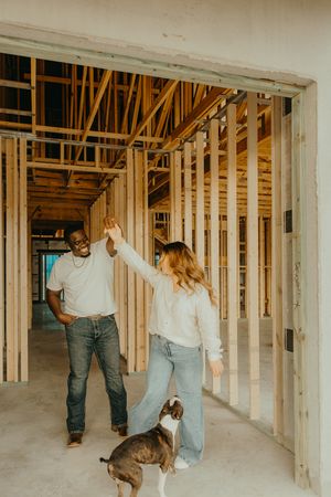 Couple dancing and spinning with their dog inside a home under construction.