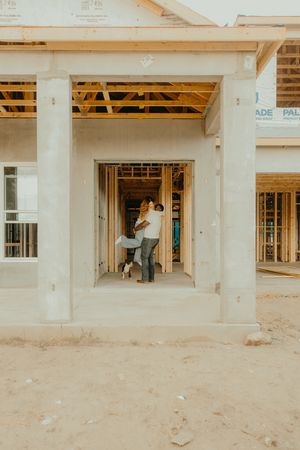 Couple embracing with their dog in the entryway of a new home under construction.