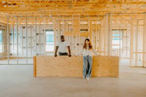 Couple posing at a kitchen island in a newly framed home under construction.
