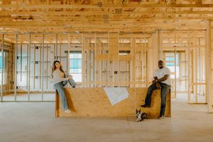 Couple sitting on a kitchen island with their dog in a home under construction.