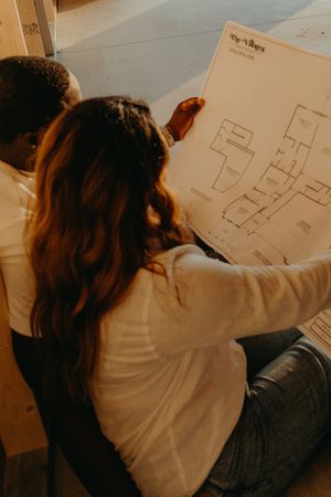 Couple sitting on floor examining new home floor plans together.