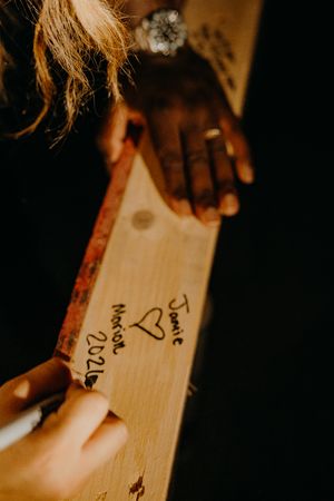 Couple signing names and date on a wooden beam at their new home construction site.