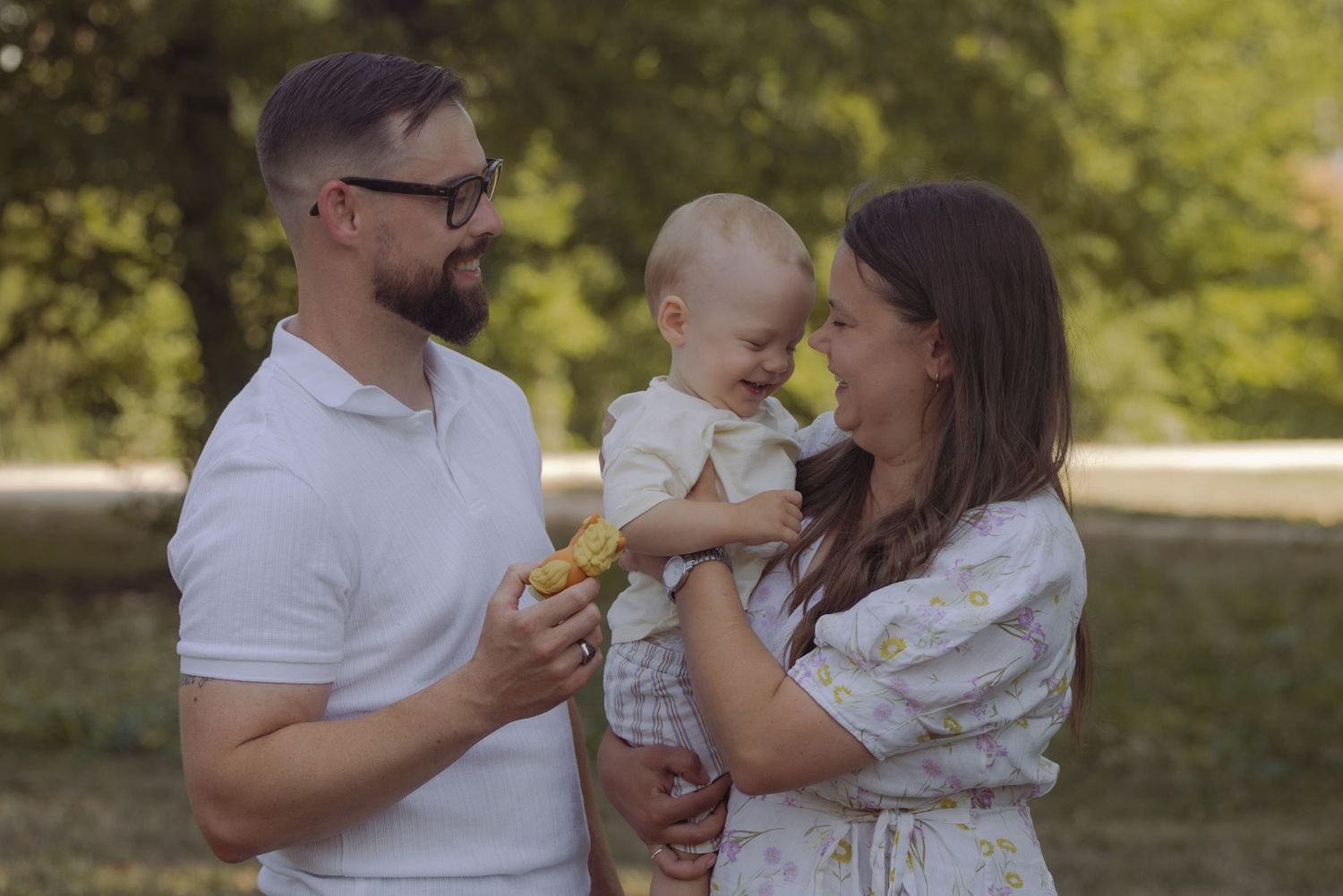Happy family with two toddlers holding a stuffed dog toy in a golden field during sunset.