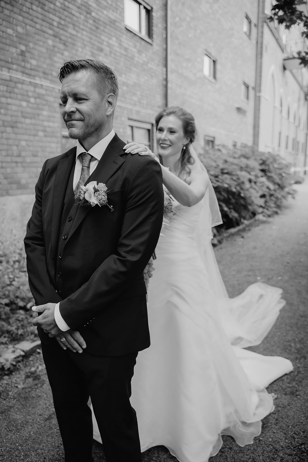 First look-fotografering i Norrköping, där bruden lägger handen på brudgummens axel medan han står med ryggen vänd mot henne.