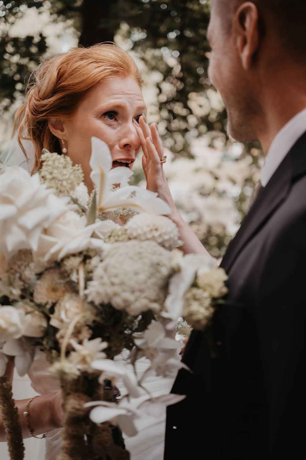 Bruden fäller tårar när hon ser sin blivande man under en first look fotografering i Strömsparken i Norrköping. Foto av Lets Bloom Media.