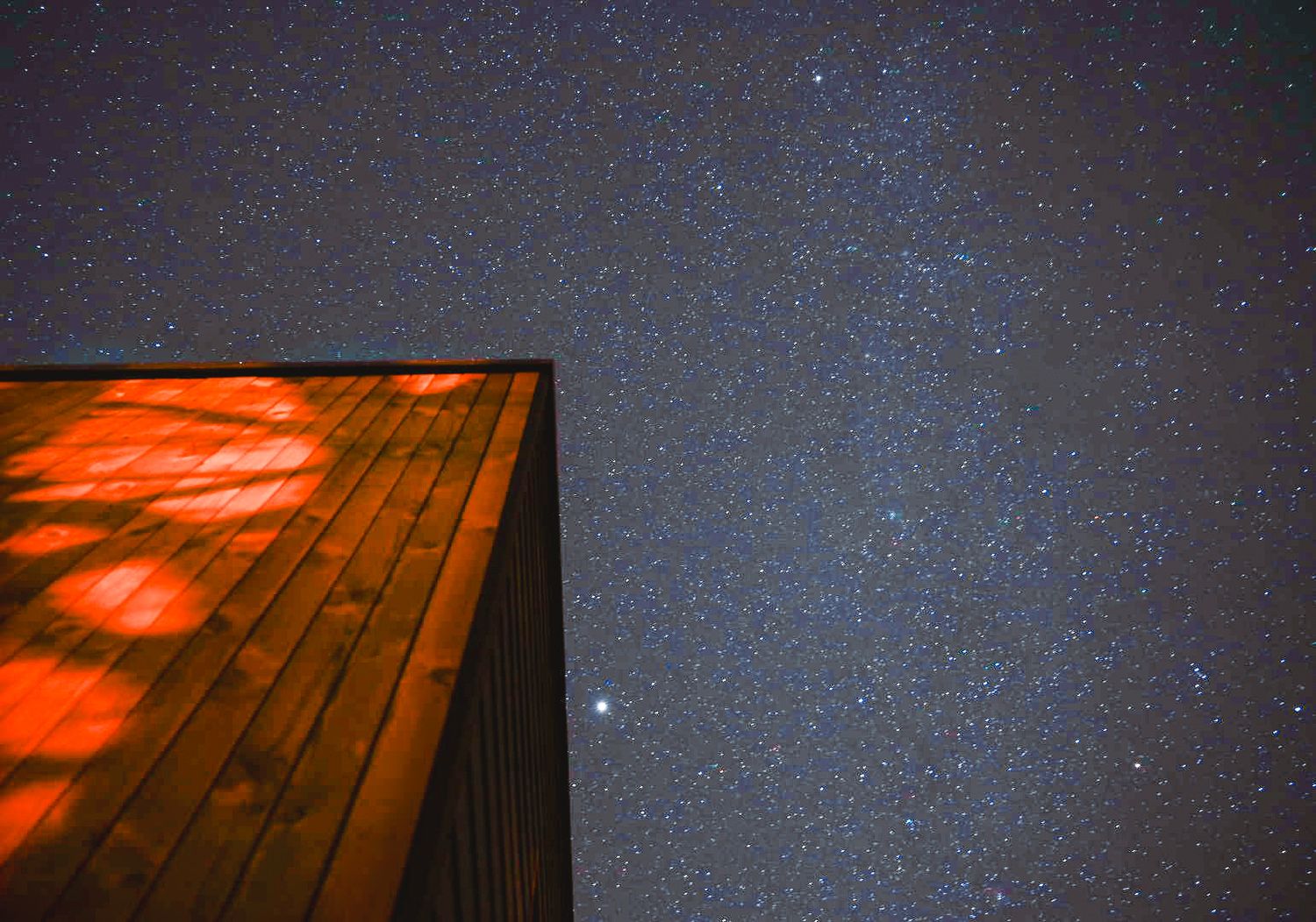 Photographie nocturne créative d'un bâtiment en bois Chimsco sous les étoiles