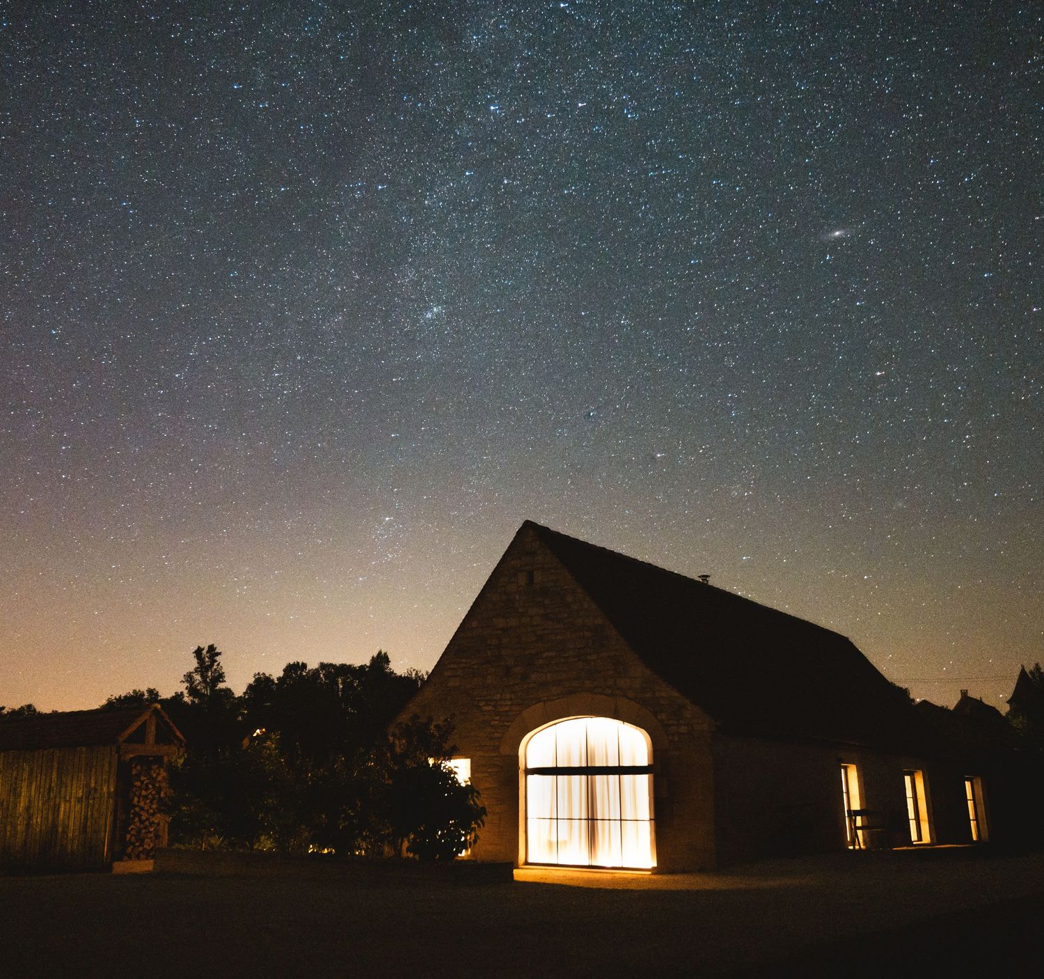 Photographie d'architecture de nuit d'une maison illuminée sous un ciel étoilé