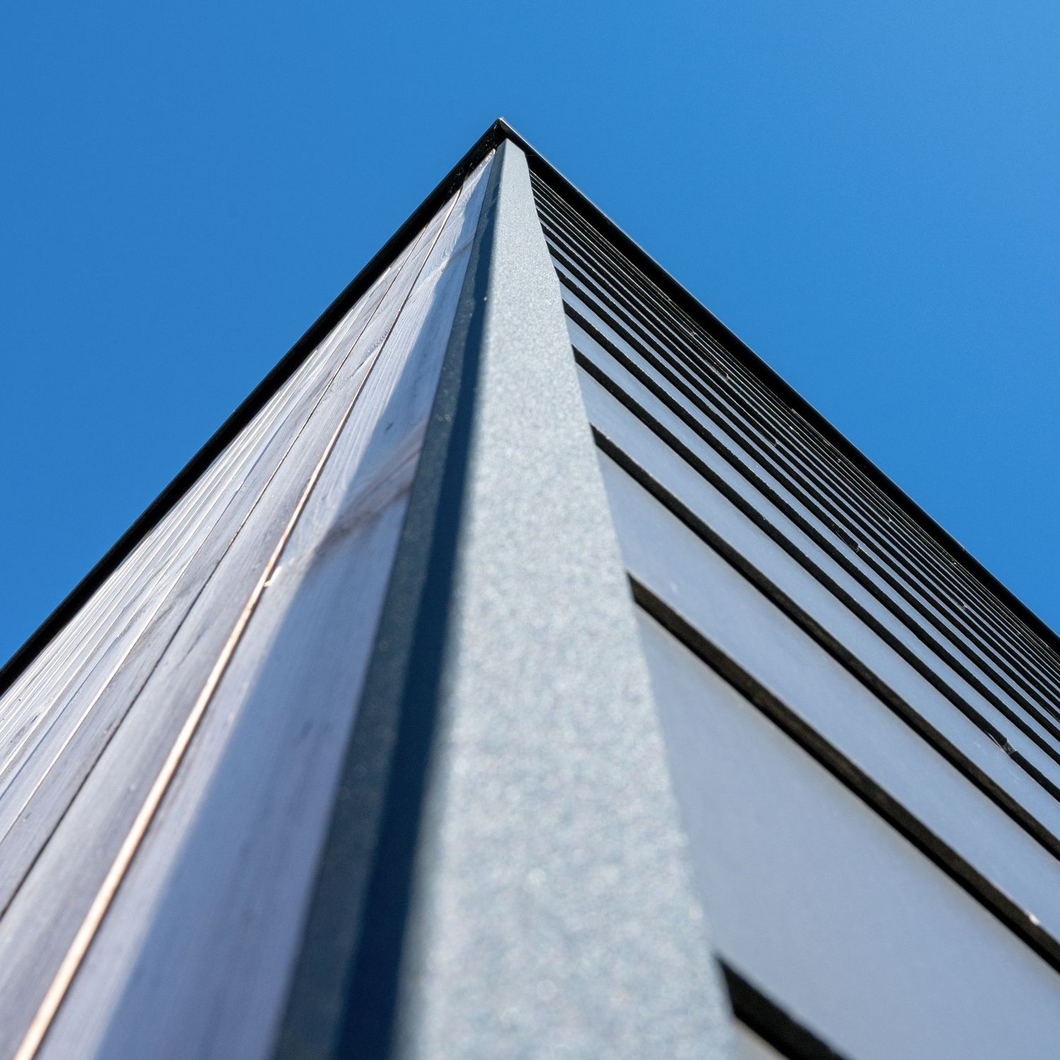 Contre-plongée géométrique sur un bâtiment moderne et ciel bleu en Wallonie Chimsco