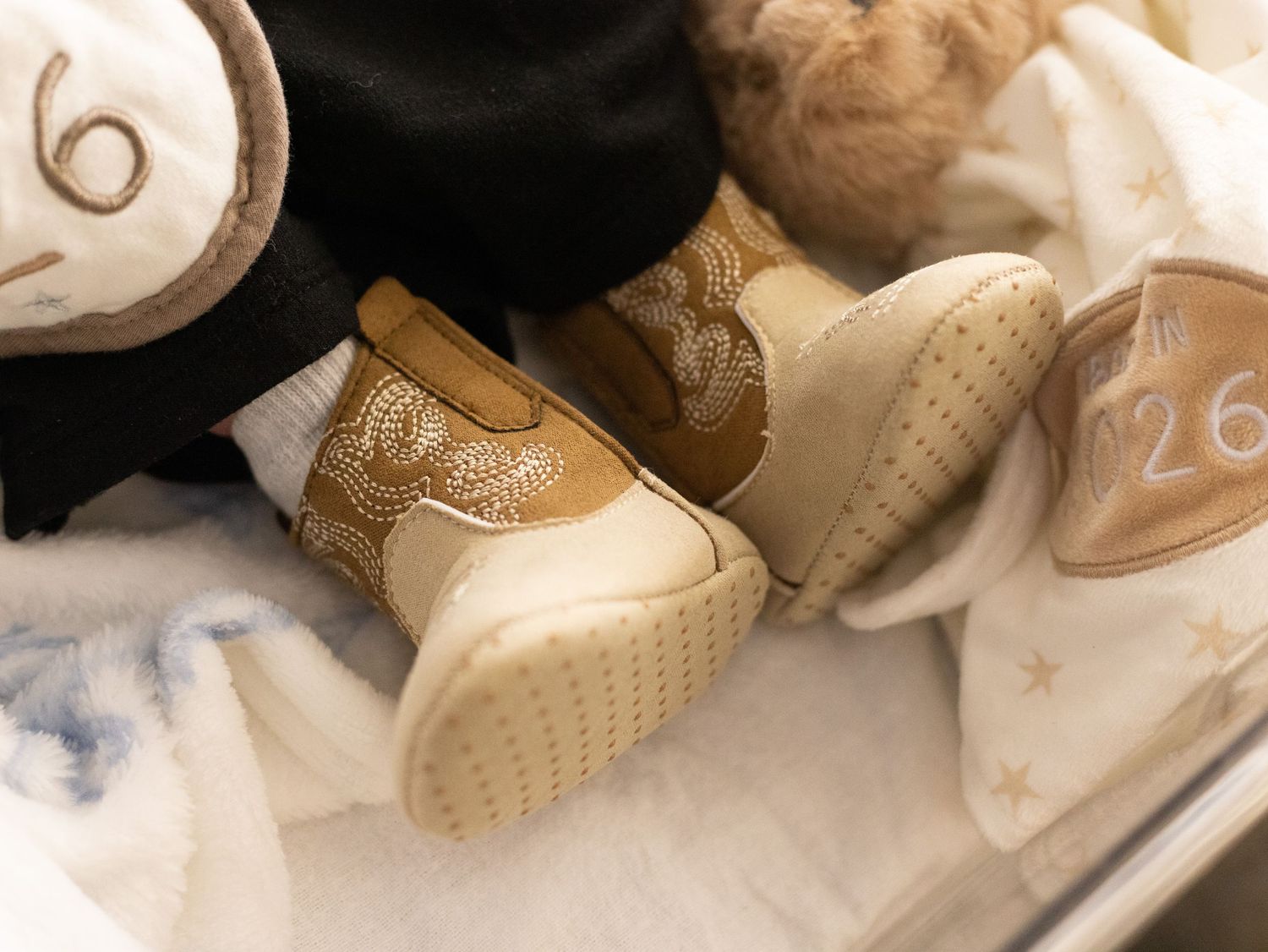 Close-up of baby booties with gold snake print design on soft blanket with star pattern.
