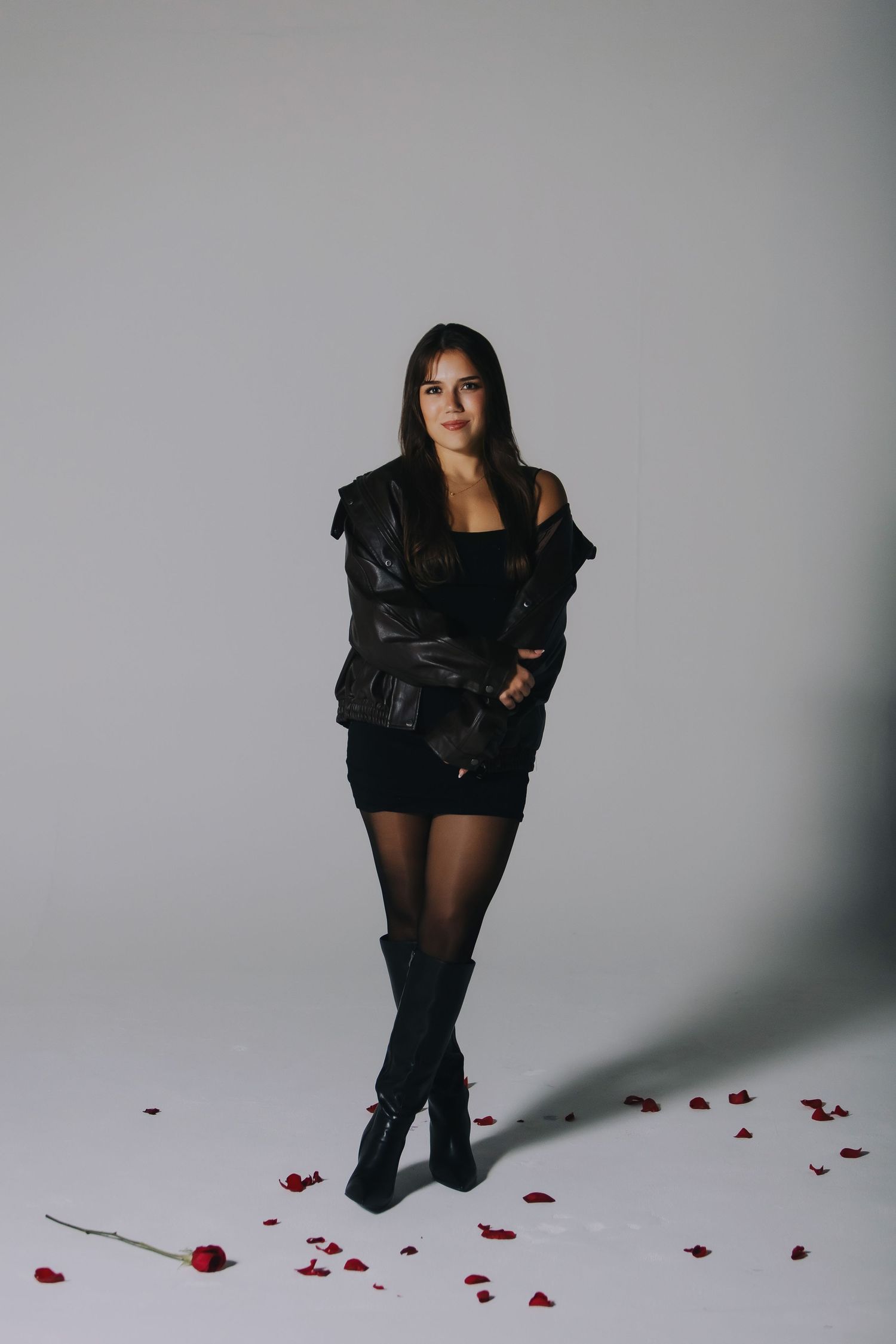 Studio portrait of a woman in a black outfit with rose petals
