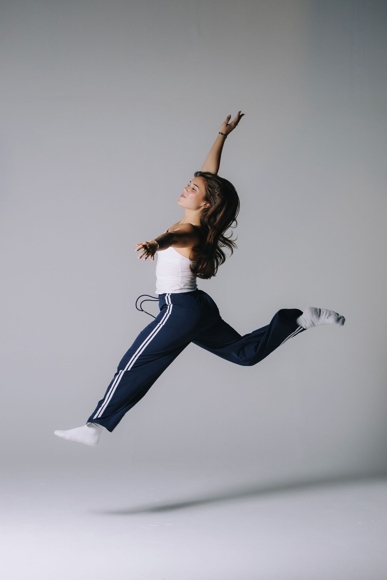 Studio action portrait of a woman jumping against a minimal backdrop