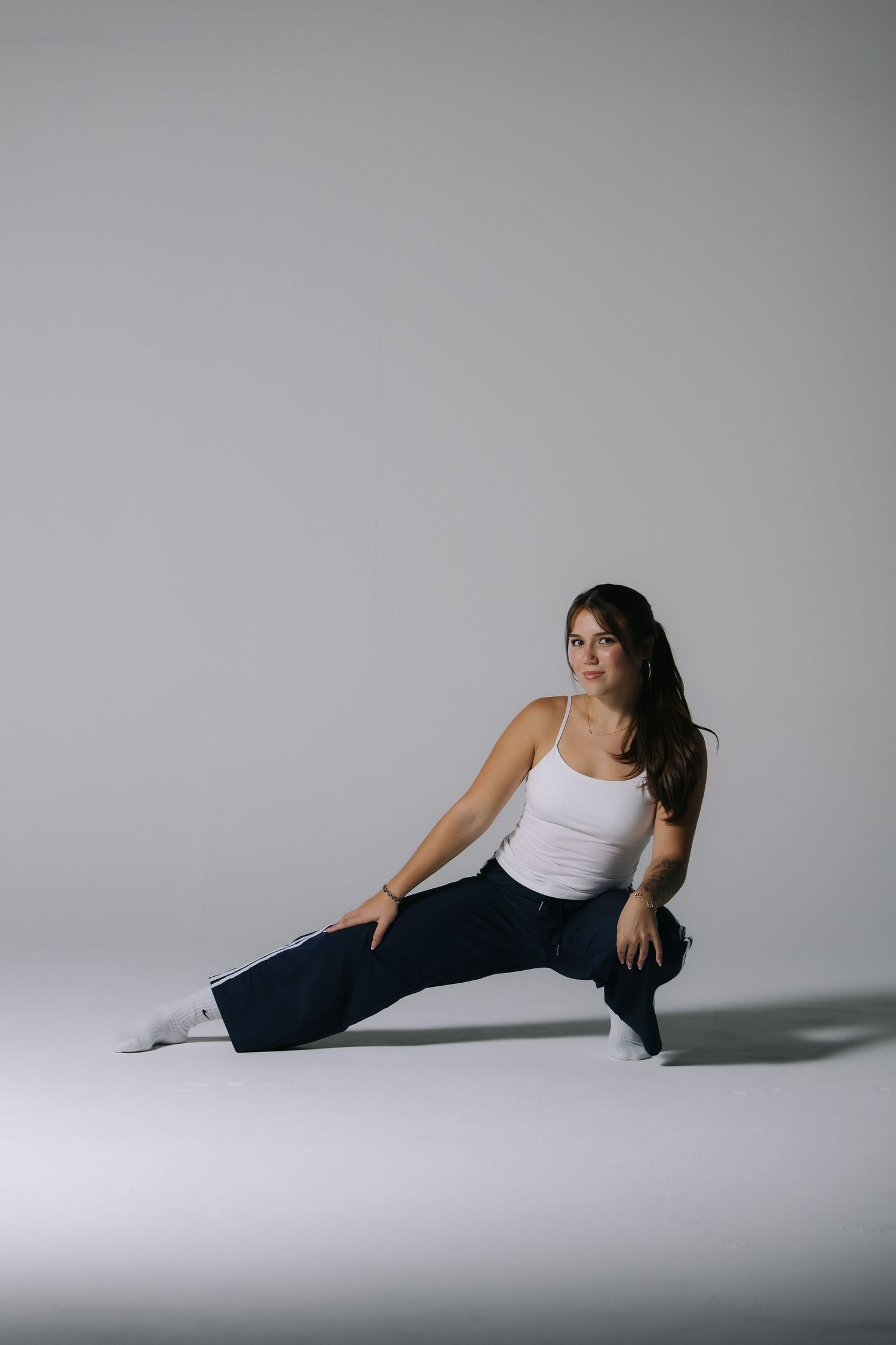 Studio portrait of a woman seated against a minimal white backdrop
