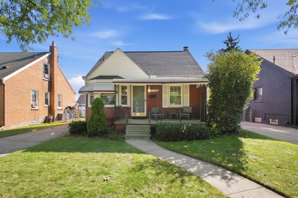 Charming brick bungalow with covered porch, manicured lawn, and mature trees in a quiet residential neighborhood.