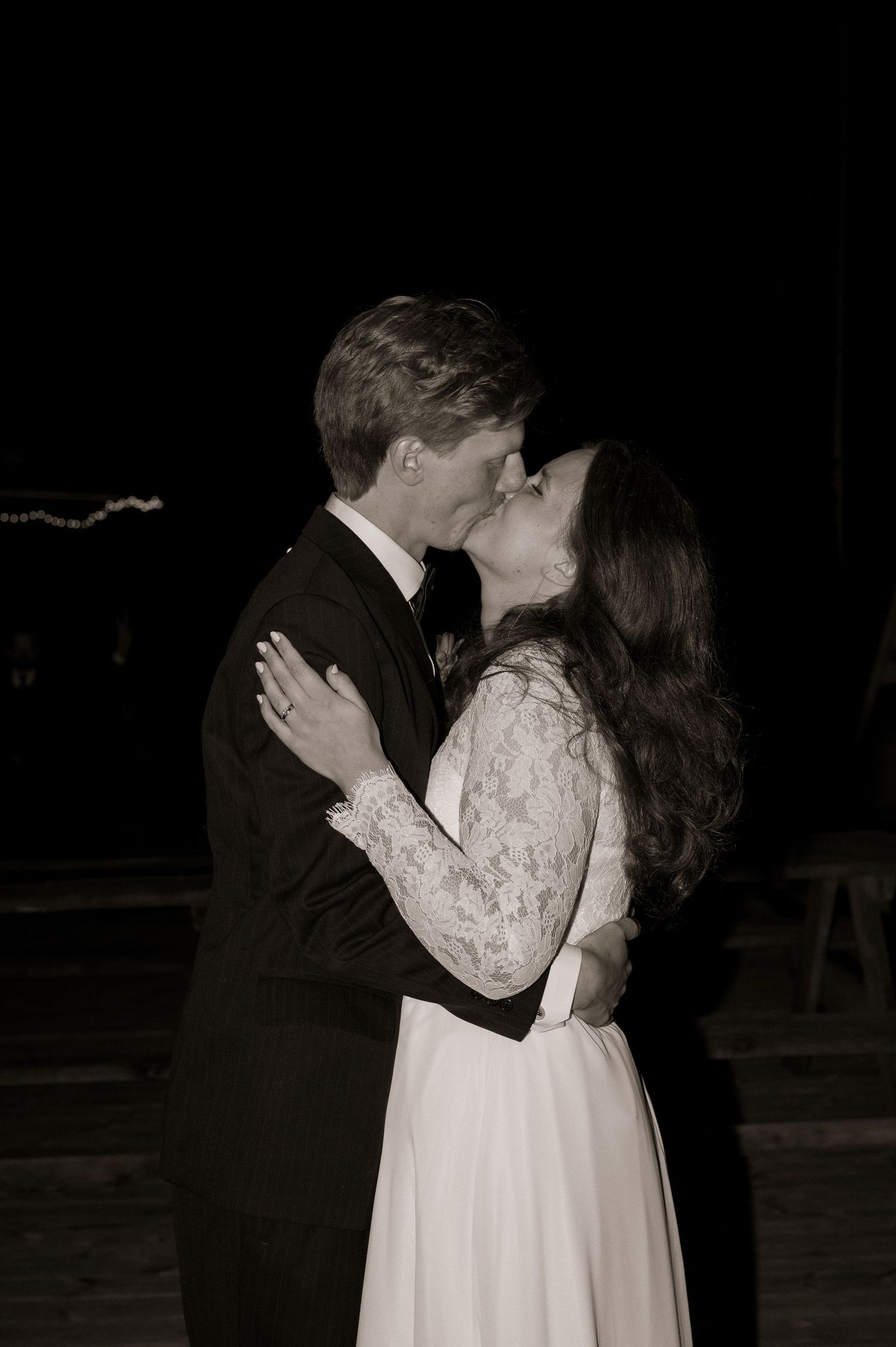 Black and white photo of a bride and groom sharing their first kiss at their wedding reception.