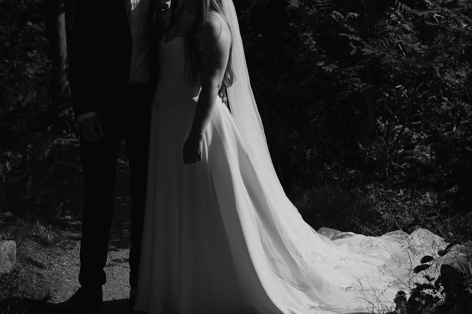 Bride and groom holding hands walking toward rocky ocean shoreline on their wedding day.