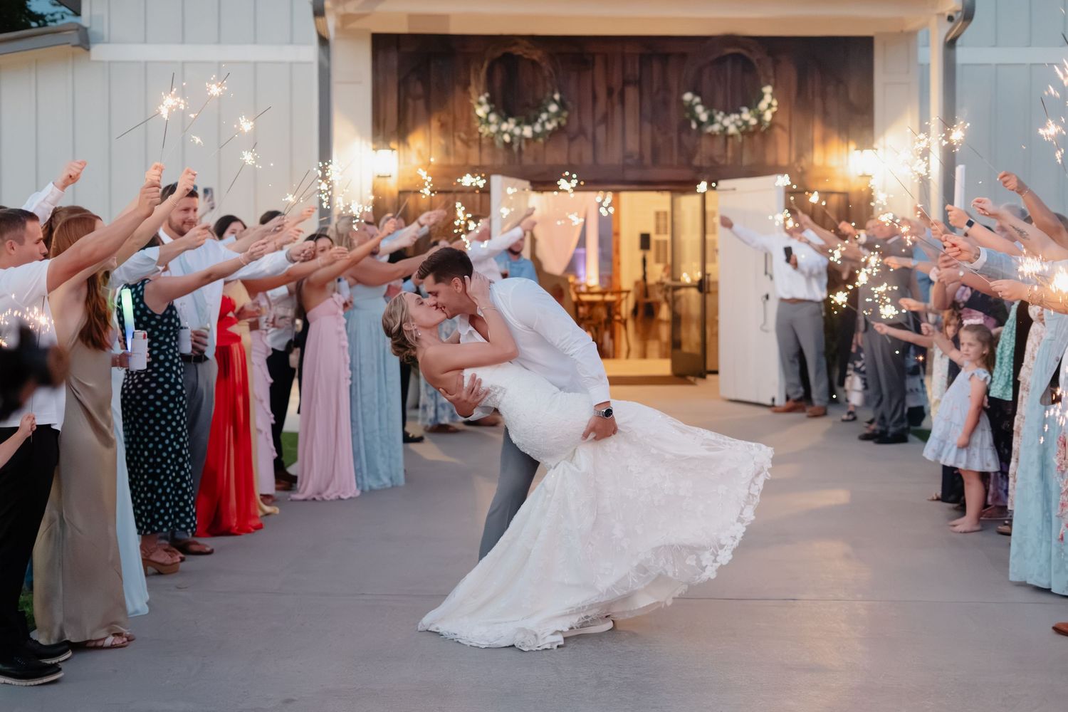Officiant in navy suit holding a book during an elegant wedding ceremony with floral arrangements in a bright venue.