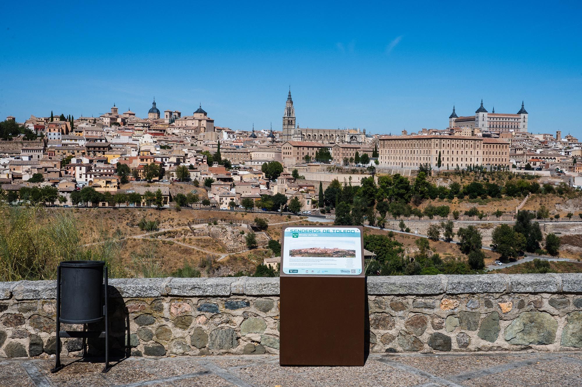 Panoramic view of Toledo, Spain skyline with historic buildings from a stone lookout point on a sunny day.