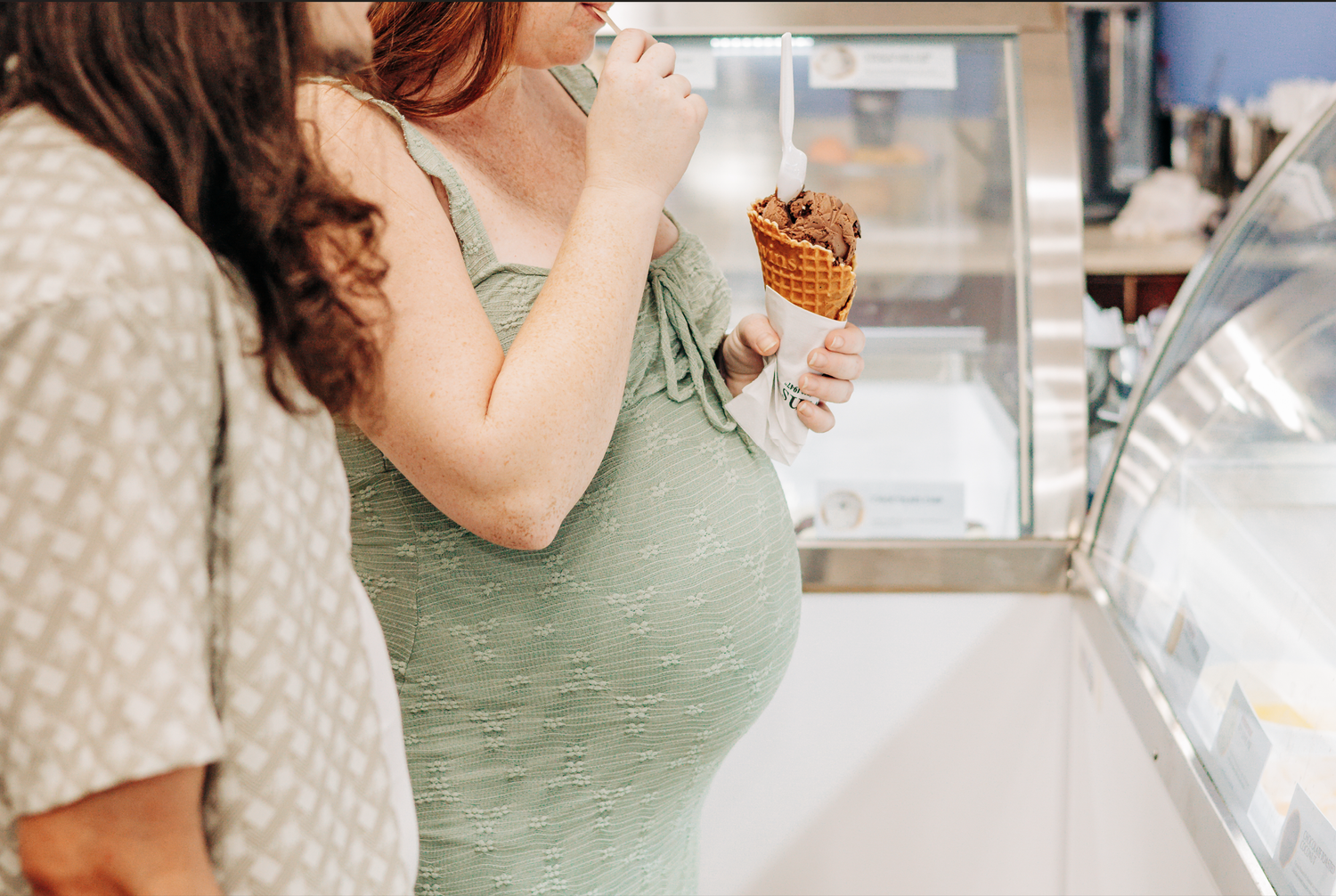 Lake Worth maternity photos of an expecting mother and her partner sharing ice cream during their beach maternity session.