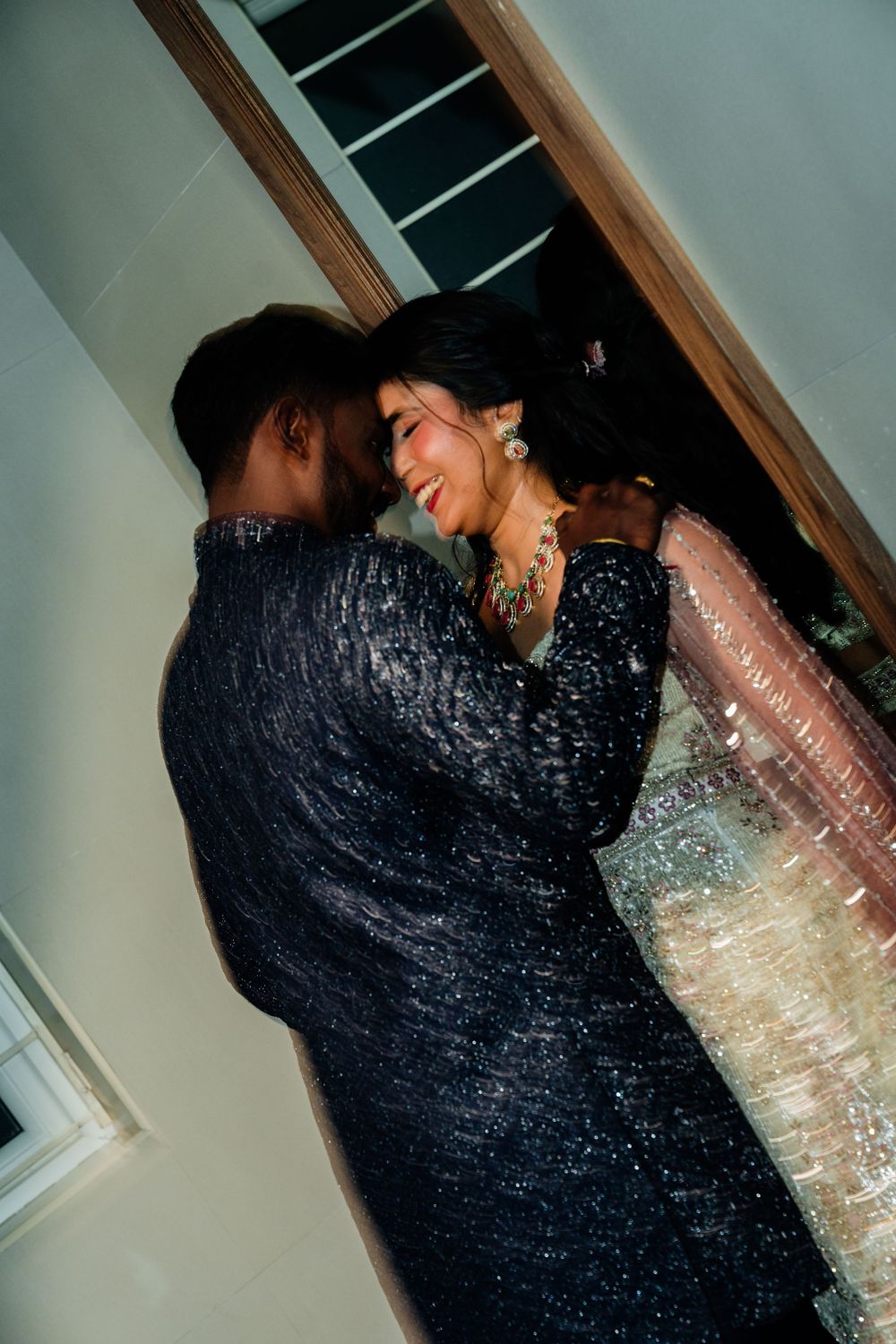 Couple shares an intimate dance moment, groom in black sequin sherwani, bride in shimmering lehenga.