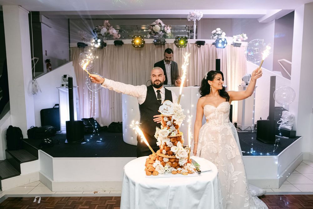 Bride and groom cutting wedding cake with sparklers at elegant reception venue.