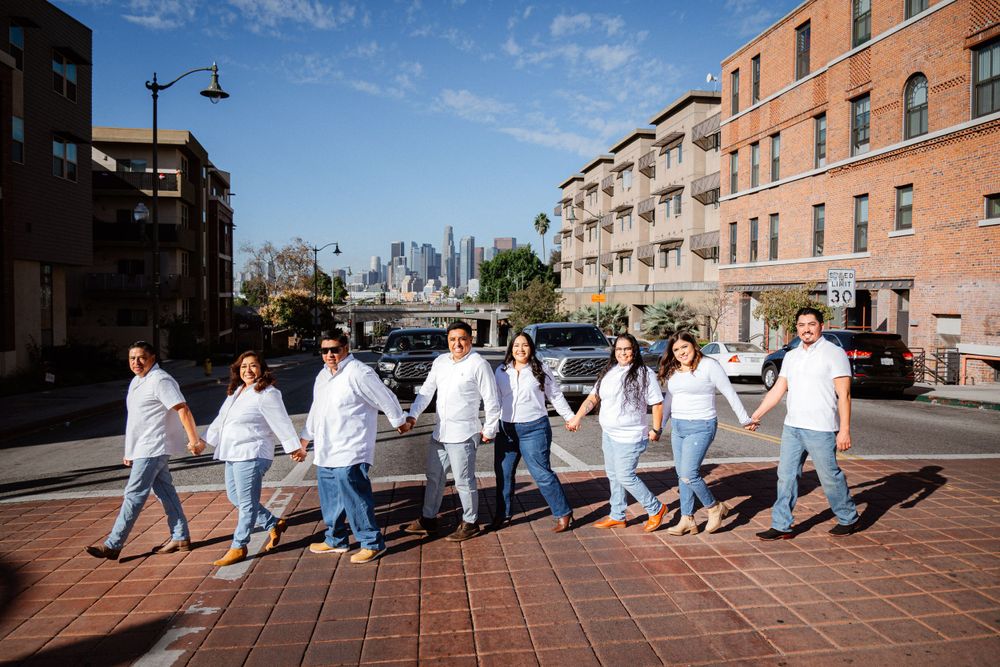 Group sitting in line on brick pavement against urban brick building backdrop.